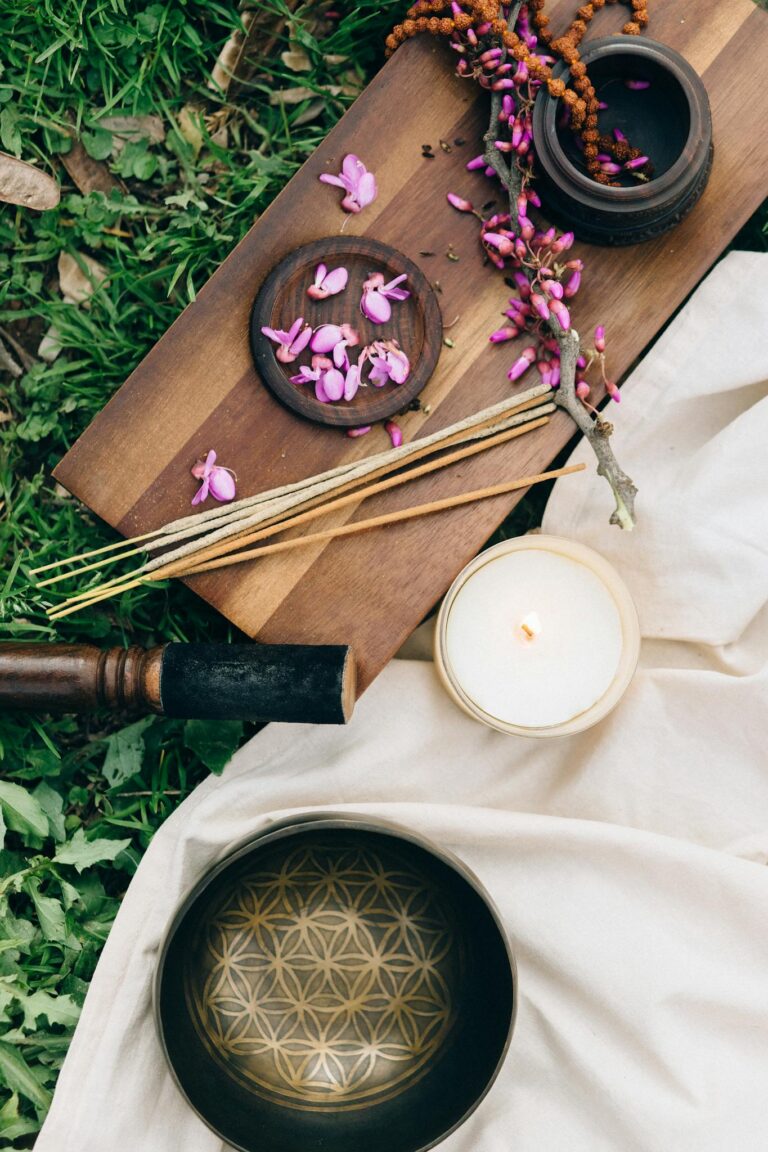 Calming outdoor meditation scene featuring incense, flowers, and a candle on a wooden board.